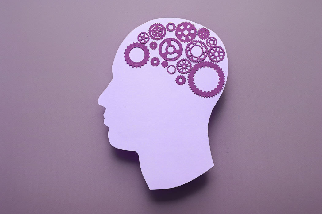 Purple silhouette head with gears inside, symbolizing thinking or ideas