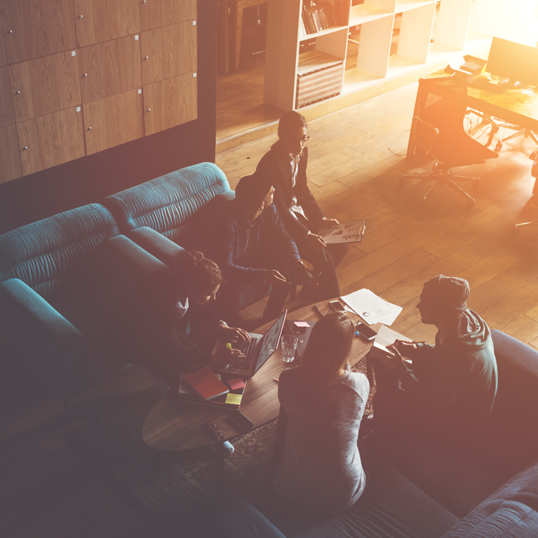 People seated around a coffee table, illuminated by sunlight. Cozy interior.