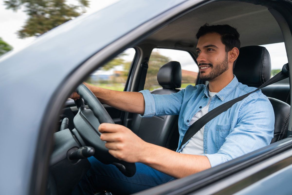 A man is driving a car with a seat belt on.