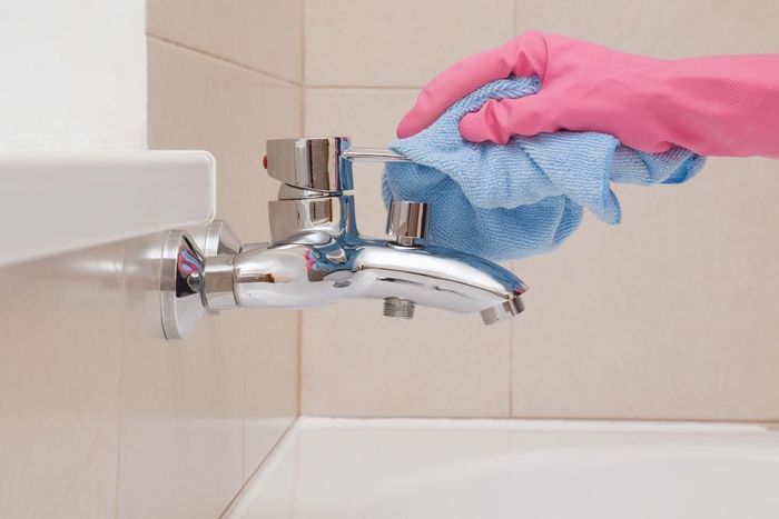 hand with a blue glove on cleaning a sink tap — Active Cleaning Service Maitland, NSW