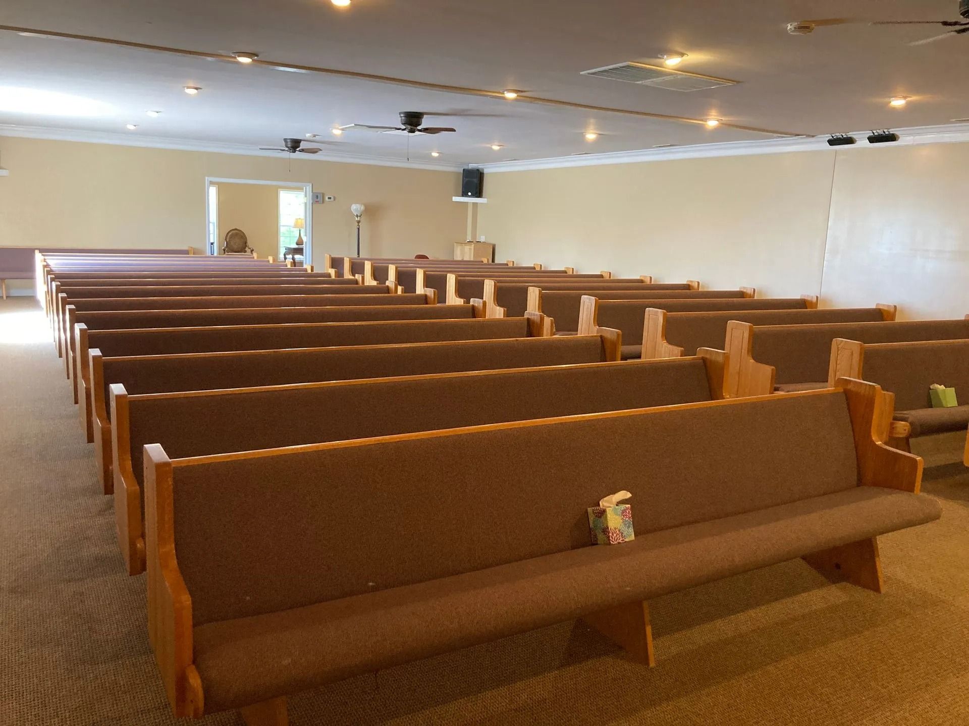 Empty church sanctuary with rows of wooden pews under soft ceiling lights