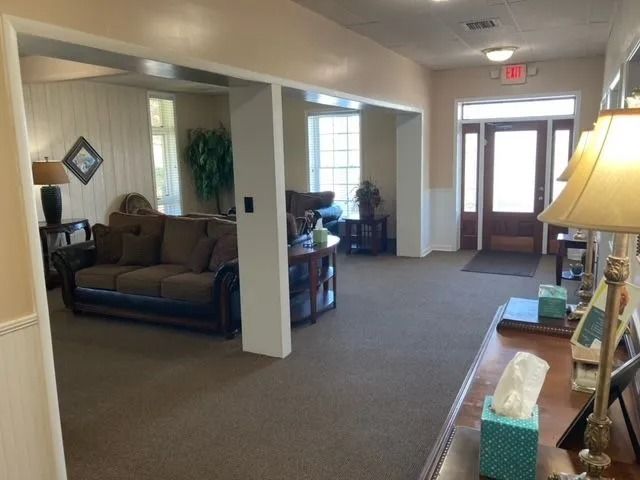 Quiet lobby with brown sofas, beige carpet, a lamp, and a front entrance door.