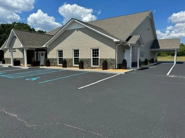 Single-story beige building with white trim and empty parking lot under a blue sky