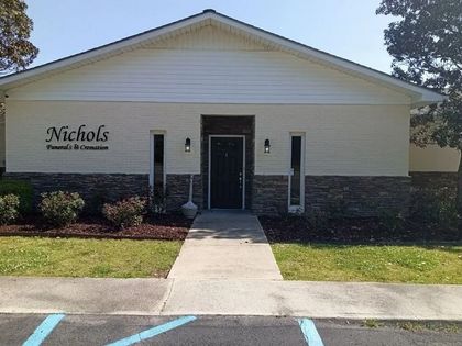 Front view of Nichols Funeral Home, a white building with a central entrance and concrete walkway.