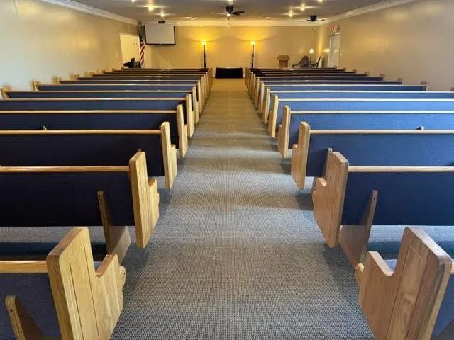 Empty church pews facing the altar in a softly lit sanctuary