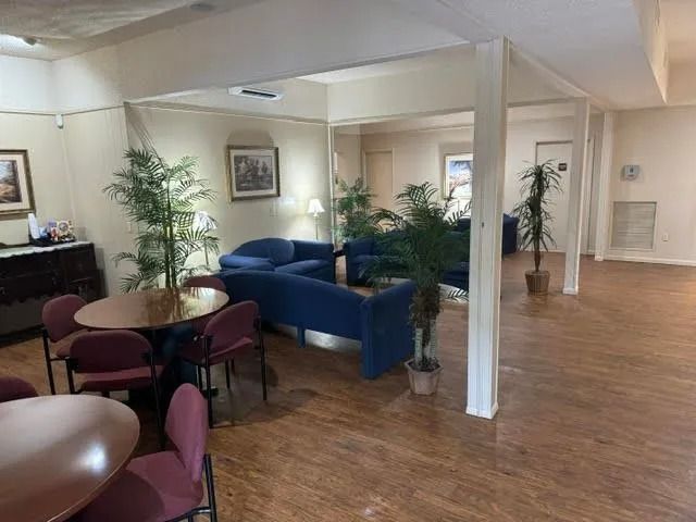 Quiet lounge area with blue sofas, round table, potted plants, and wood flooring