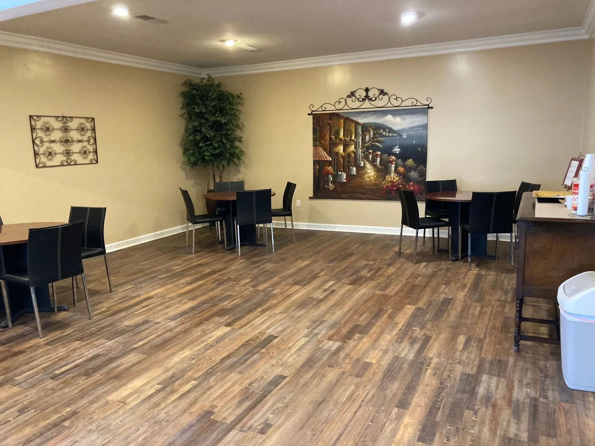 Empty banquet room with wood-patterned floor, black tables and chairs, and wall decor
