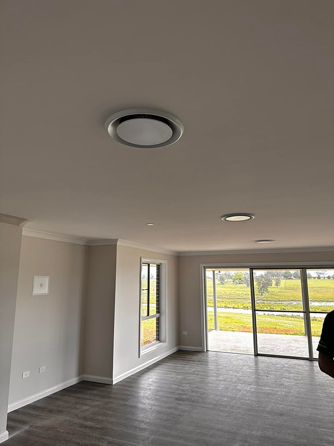 An Empty Living Room With Hardwood Floors And A Ceiling Light — Aircon Mid North Coast in Old Bar, NSW