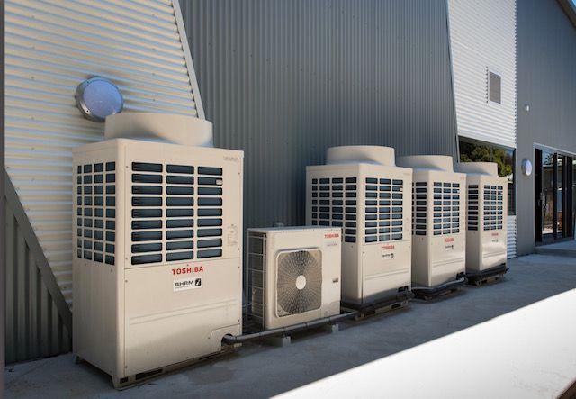 A Row Of Air Conditioners Are Lined Up On The Side Of A Building — Aircon Mid North Coast in Forster, NSW