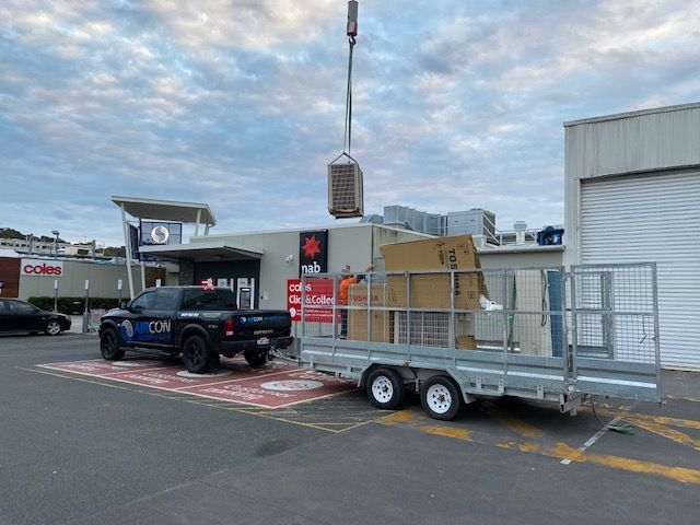 A truck is towing a trailer with boxes on it in a parking lot — Aircon Mid North Coast in Forster, NSW