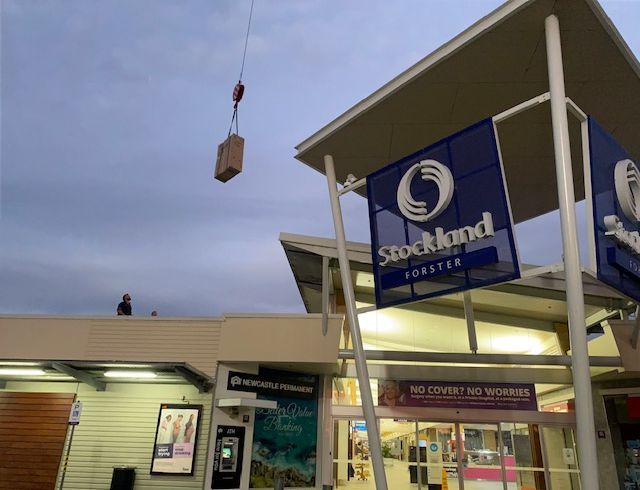 A Stockland Store With A Crane Lifting A Box — Aircon Mid North Coast in Forster, NSW