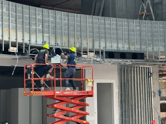Two Construction Workers Are Working On A Lift In A Building — Aircon Mid North Coast in Forster, NSW