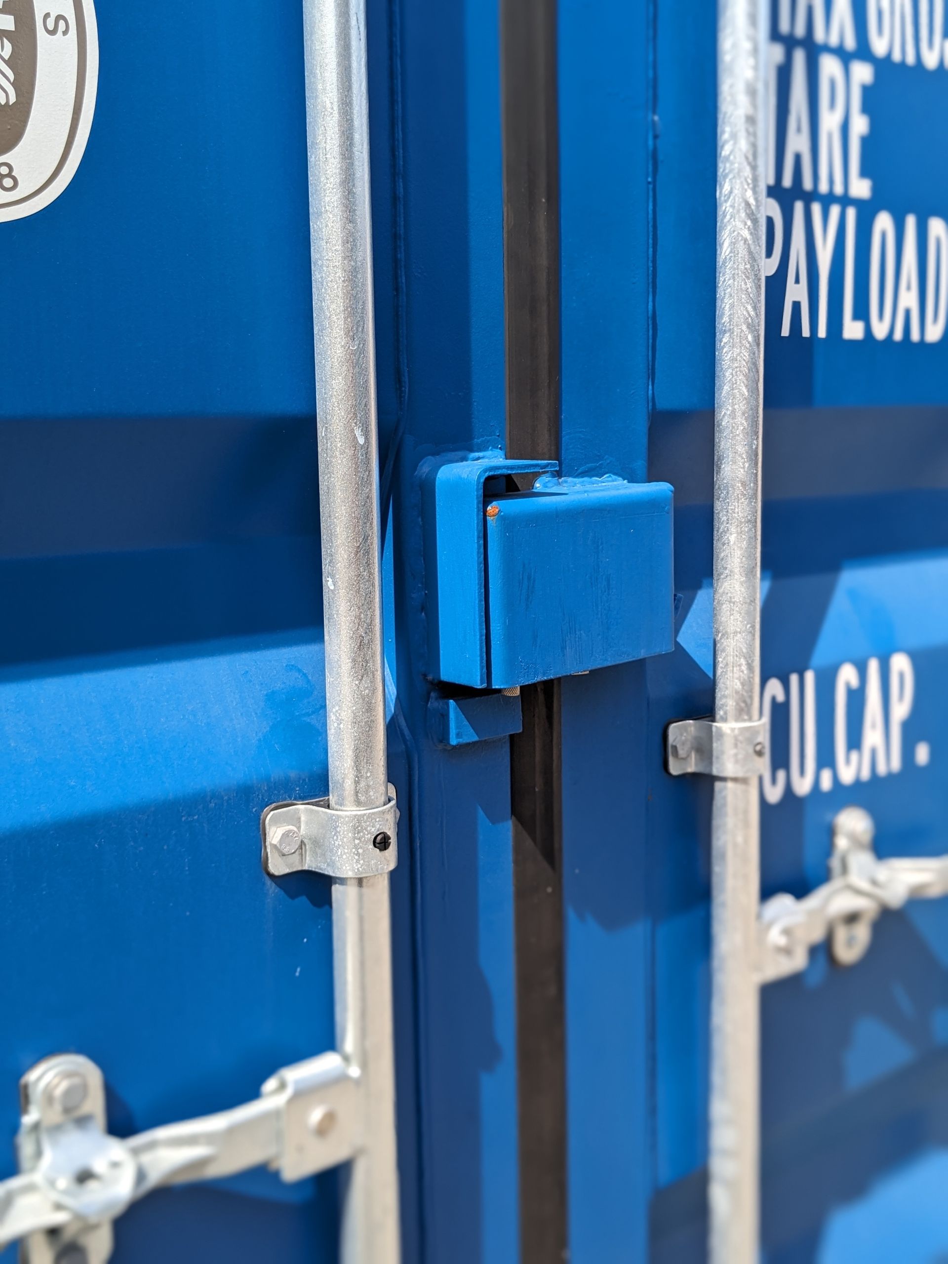 Close-up of a blue freight container door with metal latch hardware and white markings
