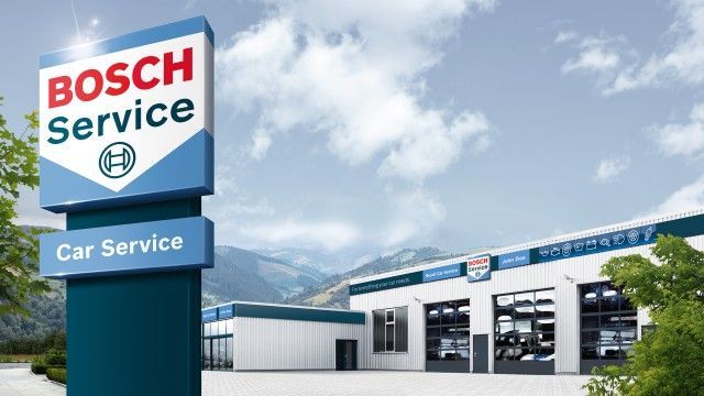 Insegna del centro assistenza Bosch Service accanto a un moderno edificio per riparazioni auto sotto un cielo azzurro.