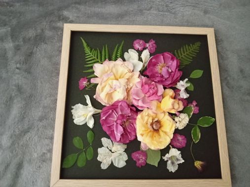 Framed floral painting with pink, cream, and yellow flowers on a dark background