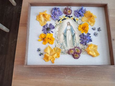 Framed pastel floral arrangement on a dark background, with soft pink, white, and blue flowers.