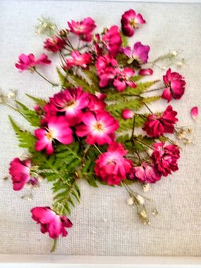 Pink and white flowers with green foliage arranged on beige fabric