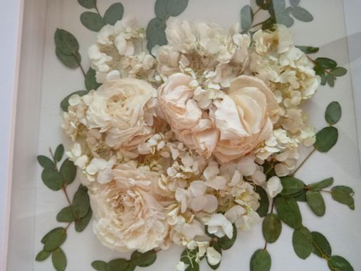 Cream and white floral arrangement with roses and greenery on a light background