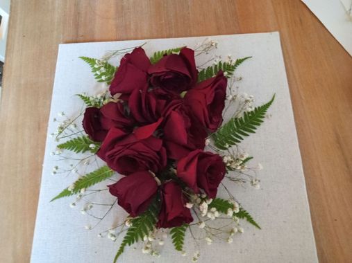 Bouquet of deep red roses with white filler flowers on a light wooden table