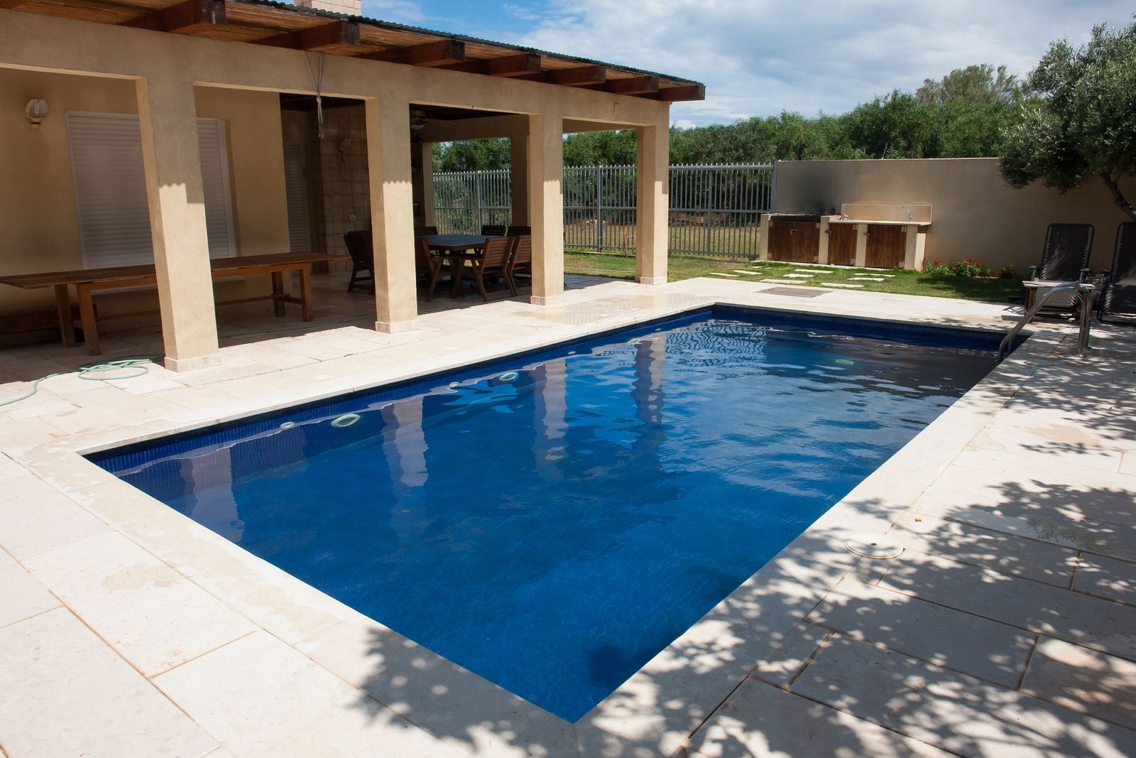 Backyard patio with a blue swimming pool beside a covered terrace