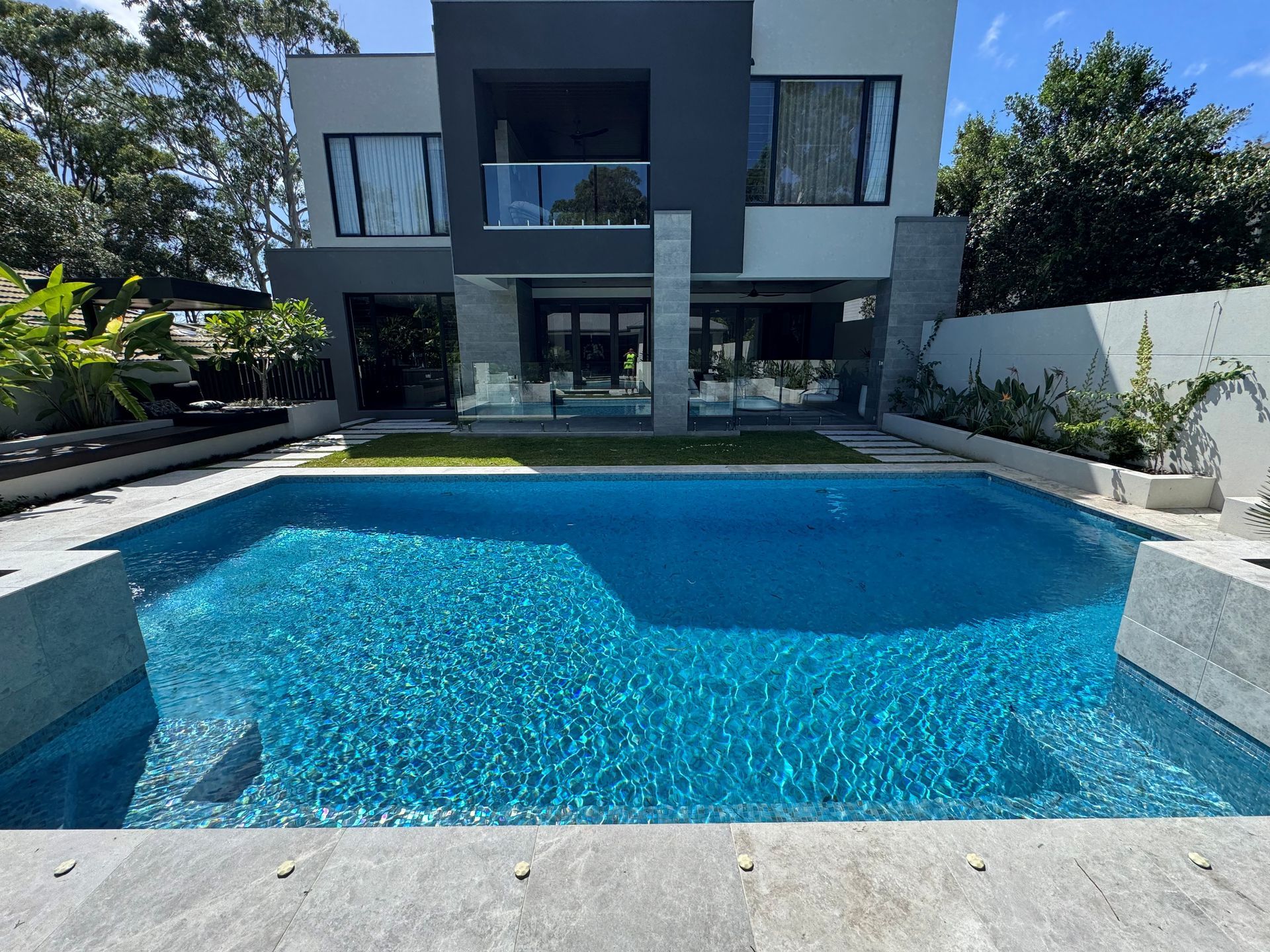 Modern two-story house with a blue swimming pool in the foreground
