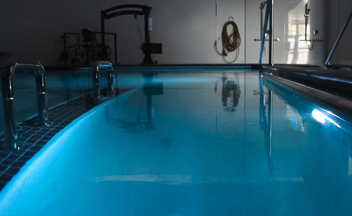 Indoor swimming pool with bright blue water and metal handrails