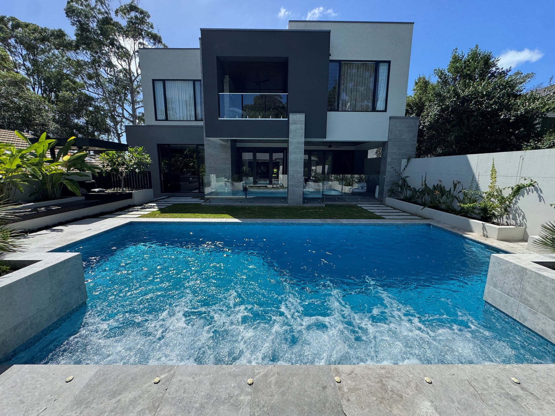 Modern two-story house with a blue swimming pool and patio in the foreground
