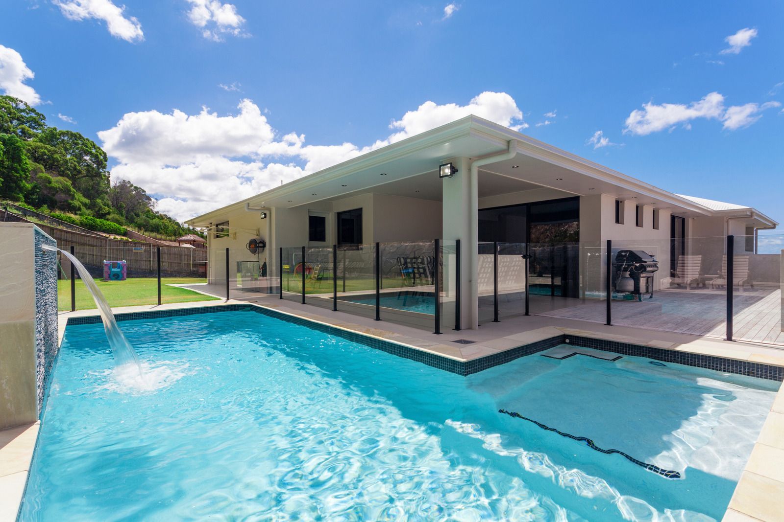 Backyard pool with spa, patio cover, and outdoor seating beside a modern home