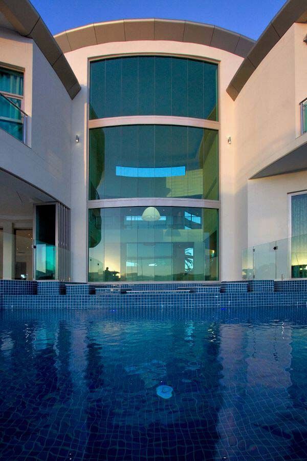 Modern courtyard with a blue-tiled pool and large glass facade between beige buildings