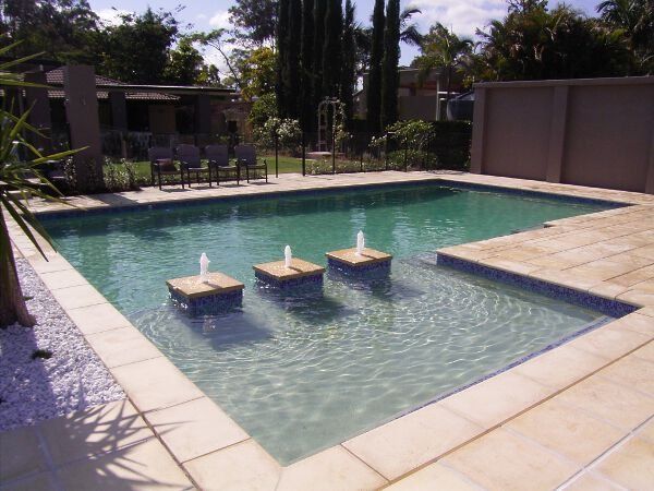Rectangular outdoor swimming pool with three submerged stools on a sunny patio