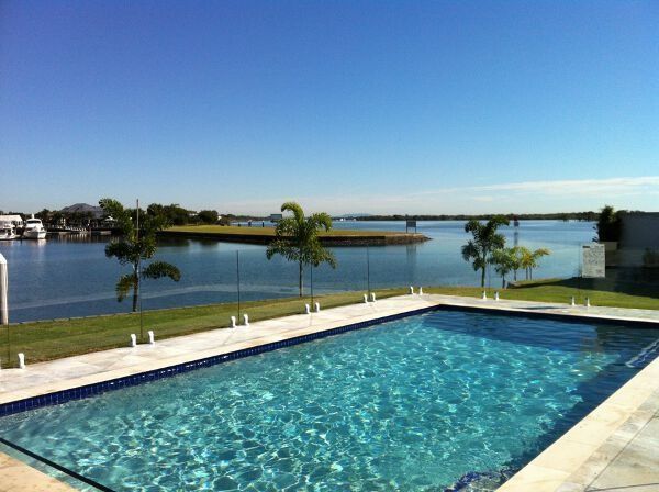 Pool overlooking a calm waterfront under a clear blue sky