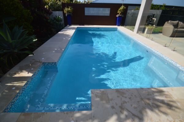 Modern backyard swimming pool with blue water and a patio deck