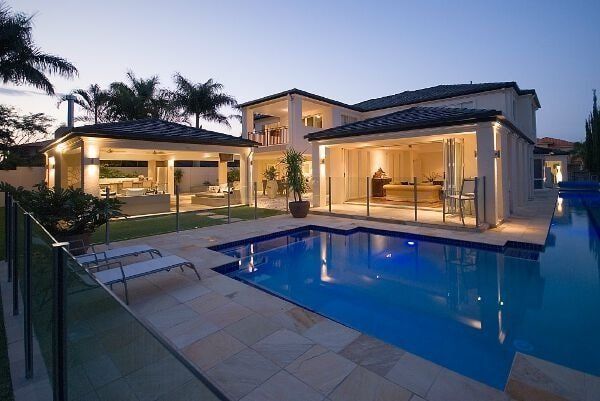 Luxury house patio with lit pool at dusk and palm trees
