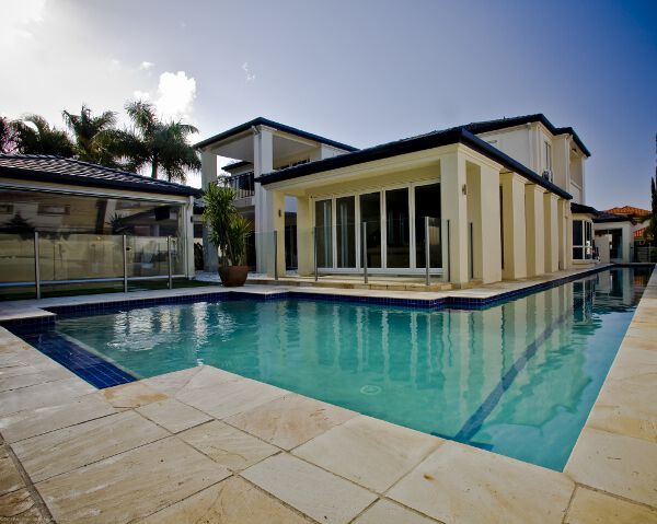 Modern home with a turquoise swimming pool and stone patio under a bright sky