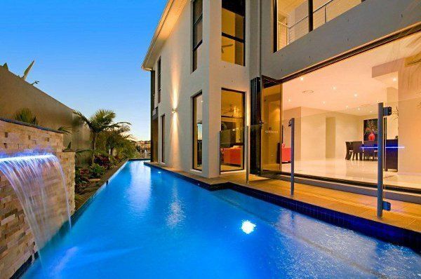 Modern house with an infinity pool beside a waterfall at dusk