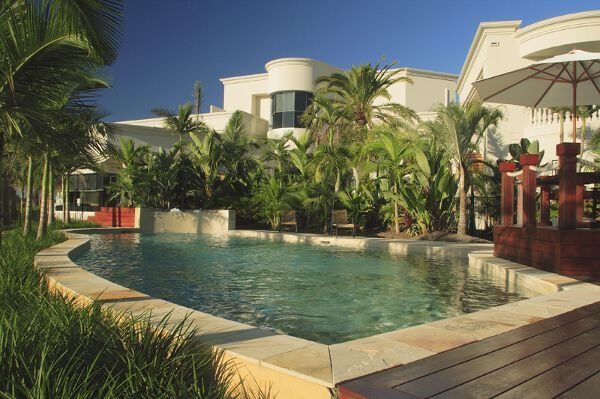 Resort pool with palm trees, lounge chairs, and a sunny tropical patio