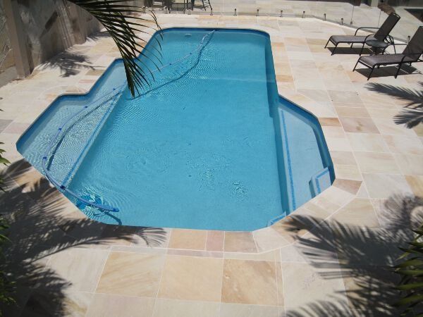 Backyard swimming pool with light blue water and stone patio surround