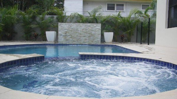 Backyard swimming pool with a bubbling spa and tropical landscaping