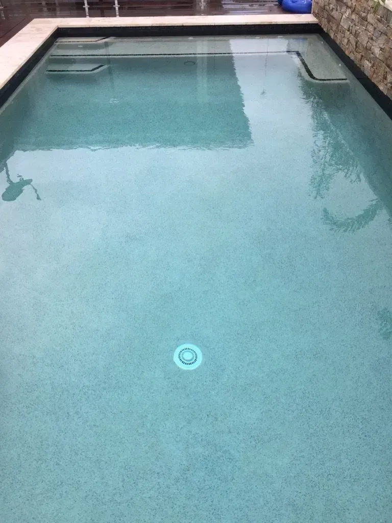 Rectangular backyard swimming pool with clear blue water and a tiled edge