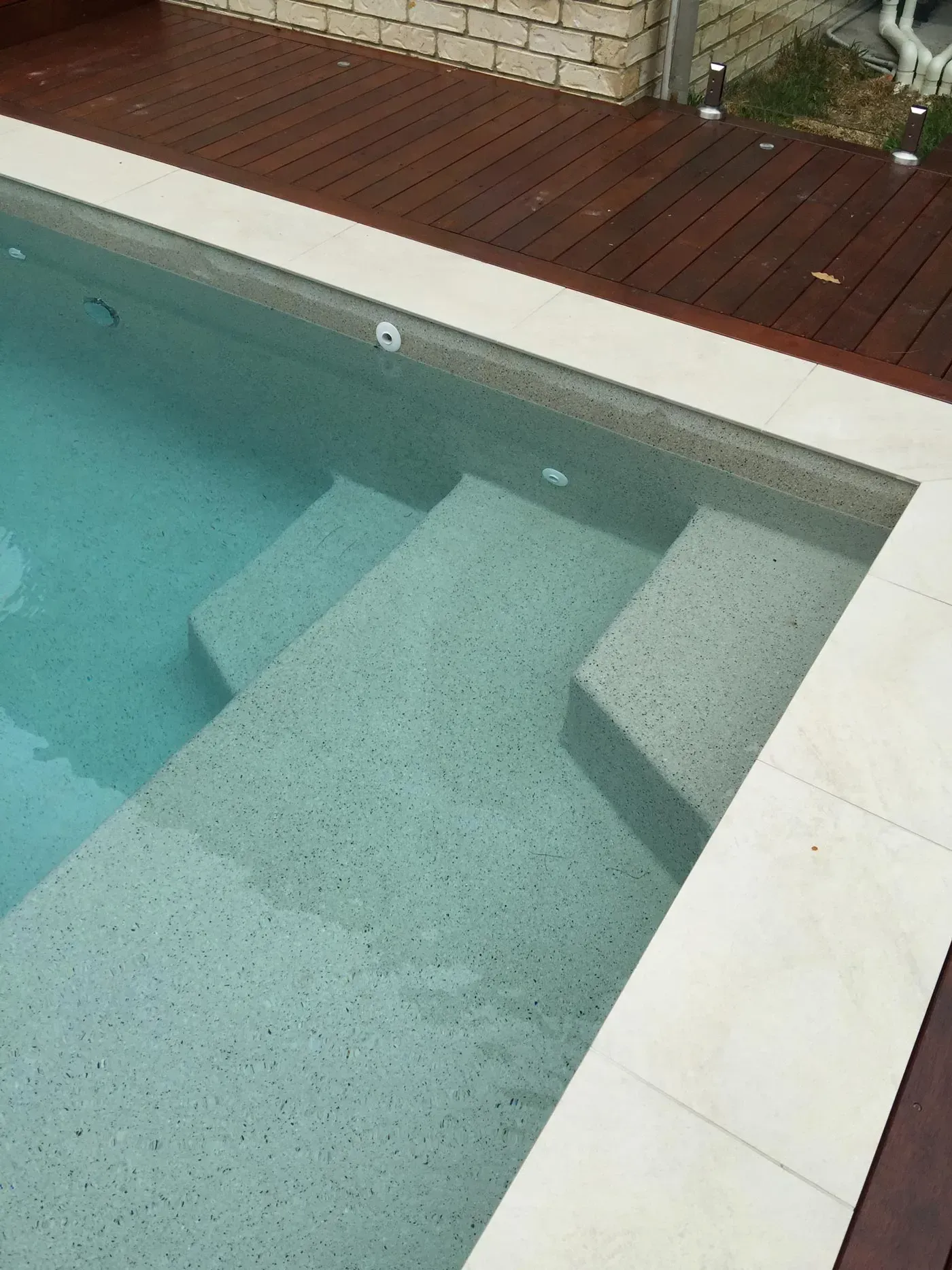 Swimming pool with submerged steps and a red deck edge.