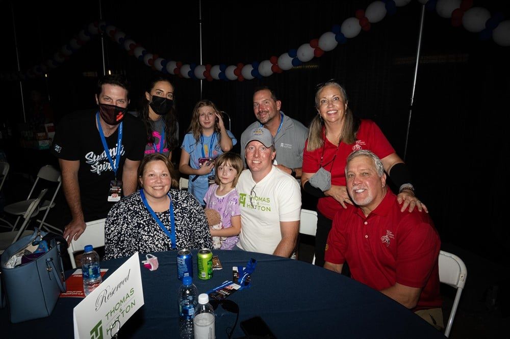 A group of people are sitting at a table posing for a picture.
