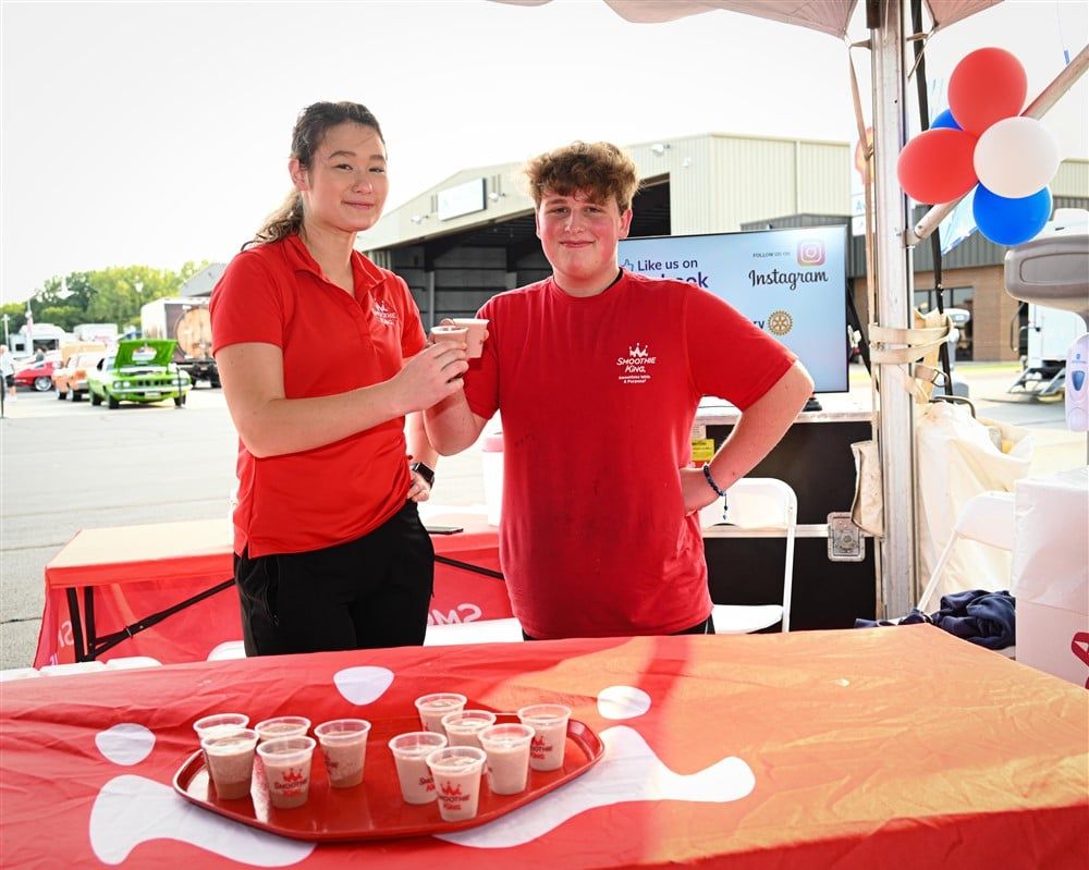 A man and a woman are standing in front of a table with cups on it.