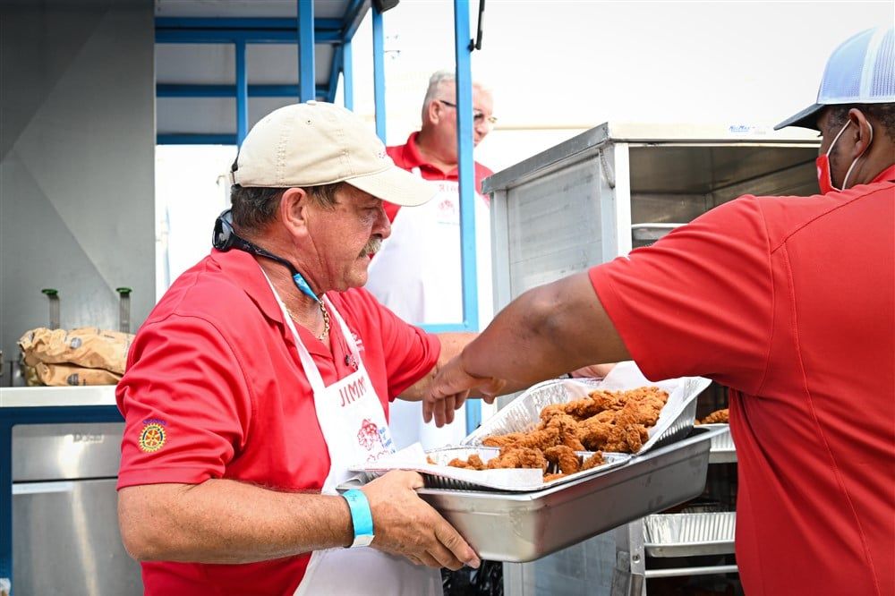 A man in a red shirt is holding a tray of fried chicken.