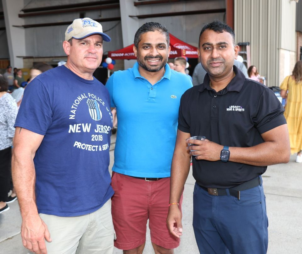 Three men posing for a picture with one wearing a shirt that says new jersey