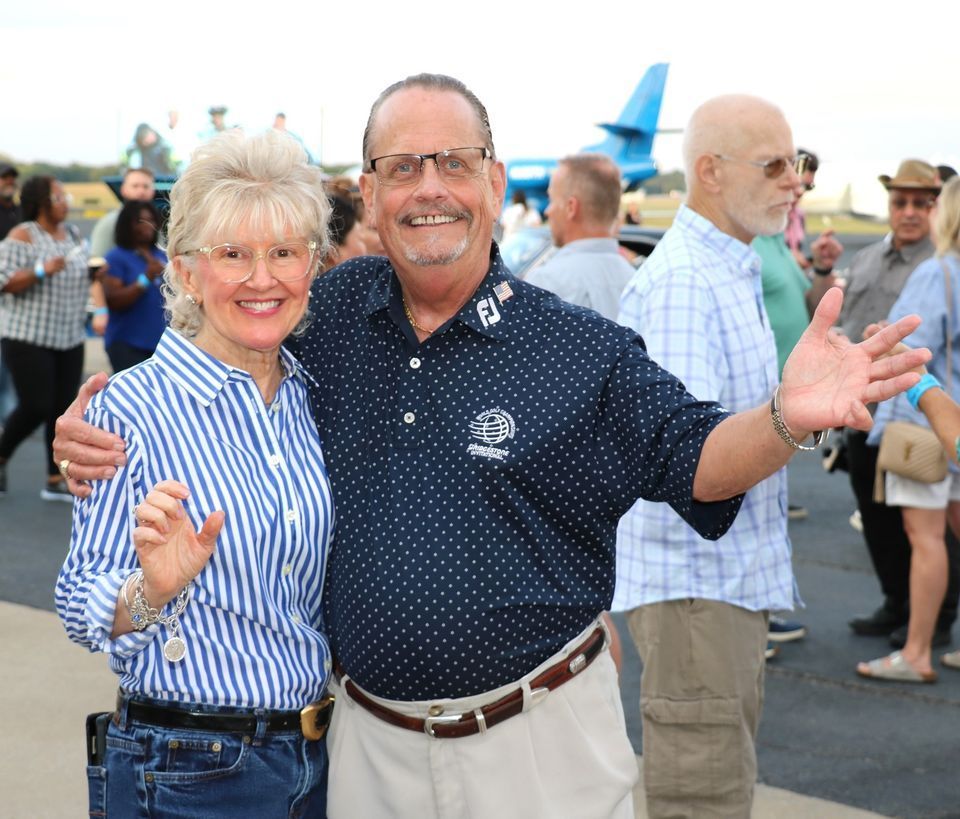 A man and a woman are posing for a picture in front of a crowd
