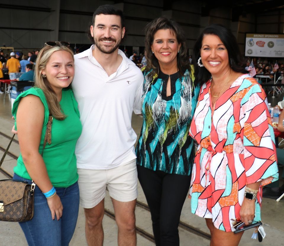 A group of people posing for a picture with one woman holding a louis vuitton purse