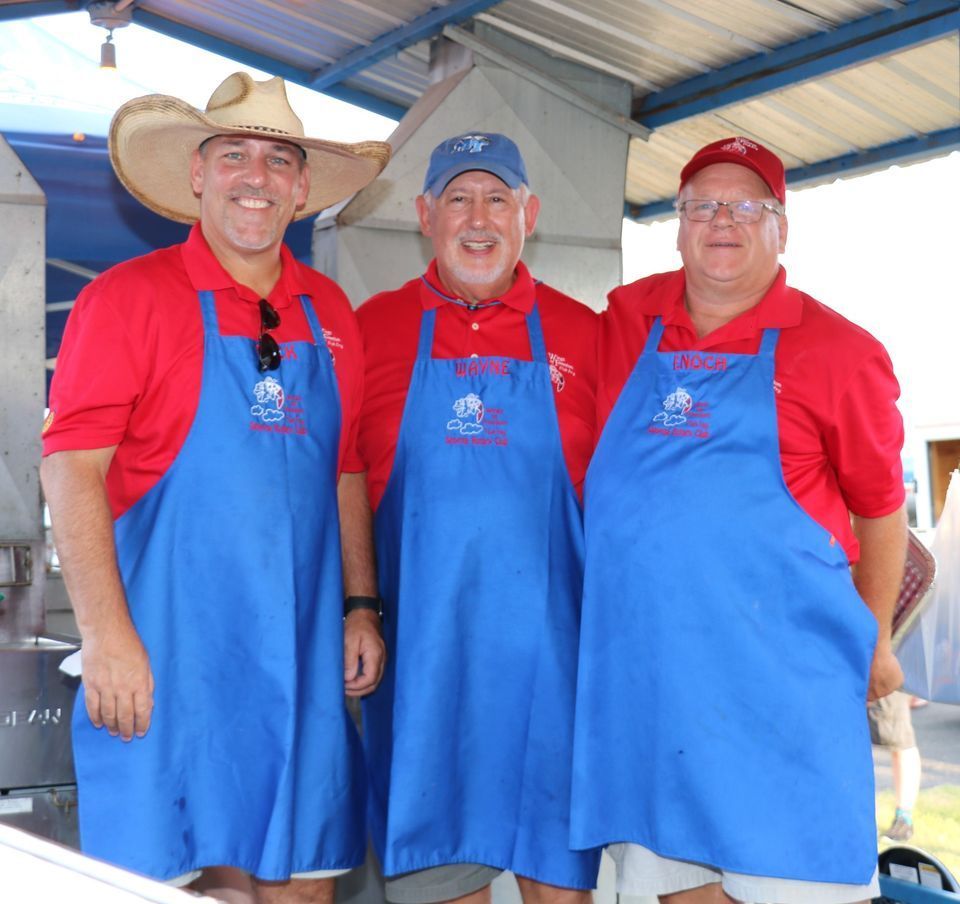 Three men wearing blue aprons and red shirts are posing for a picture