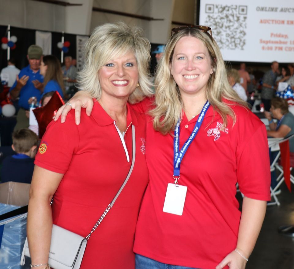 Two women in red shirts are posing for a picture