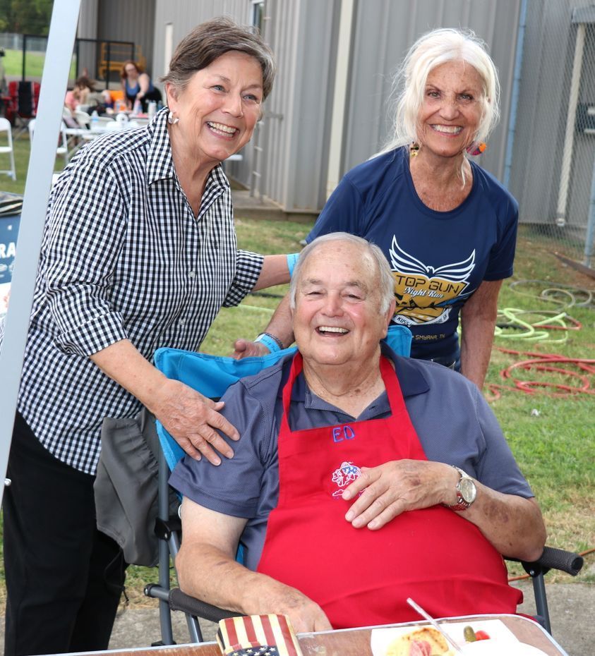 A man in a wheelchair is being helped by two women
