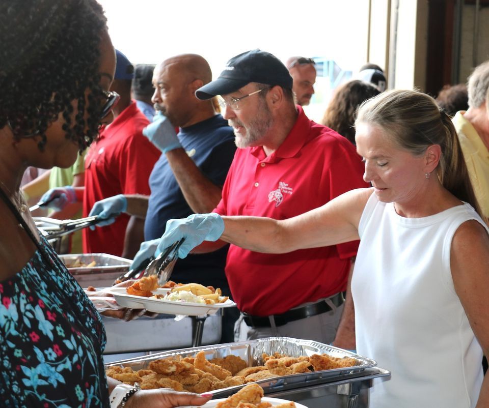 A man in a red shirt is serving food to a woman